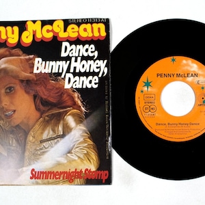 May include: A vintage vinyl record and album cover for Penny McLean's "Dance, Bunny Honey, Dance." The album cover features a woman in a gold jacket. The record label is orange with black text. The album cover also has the text "Summernight Stemp."