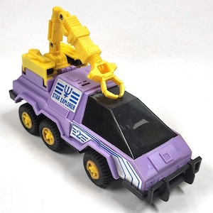 May include: Purple toy vehicle with a yellow crane arm and a black windscreen. The vehicle has white stripes and the words "Star Explorer" on the side.
