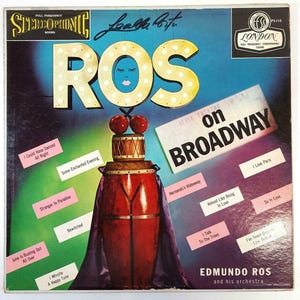 Peut inclure: Pochette de disque vinyle vintage pour "Ros on Broadway" par Edmundo Ros et son orchestre. La couverture présente un design stylisé avec le mot "ROS" en grandes lettres illuminées et une illustration centrale d'un tambour. L'album comprend des chansons comme "I Love Paris".