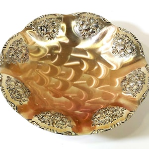 May include: A gold-colored metal serving bowl with a scalloped edge and embossed floral designs.