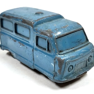 May include: A blue toy van with a white roof and windows. The van has a slightly weathered look, suggesting it is vintage.