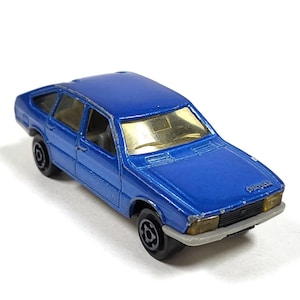 Può includere: Un'auto giocattolo in metallo blu, un modello di Chrysler. L'auto ha un parabrezza dorato e ruote nere.