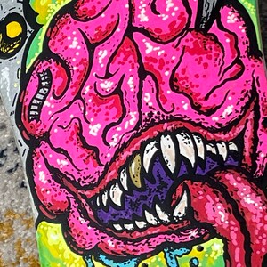 May include: A pink and green monster with a large mouth and sharp teeth. The monster's tongue is sticking out and has a pink and white pattern. The monster's eyes are black and white.