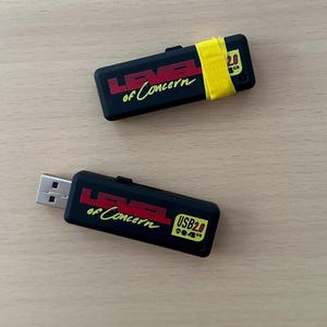 May include: Two black USB flash drives with the text "LEVEL of Concern" in red and yellow. One drive has a piece of yellow tape. The drives are USB 2.0, 4GB.