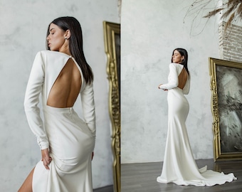 Clean and simple wedding dress with boat neck, open back, full sleeves, center slit, figure-flattering silhouette for a minimalist bride