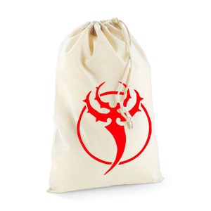 May include: A white canvas drawstring bag with a red tribal design. The design is a stylized symbol with a circle around it.