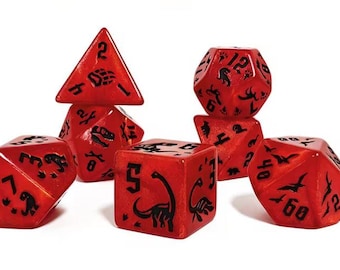 Puede incluir: Un juego de siete dados poliédricos rojos con acabado brillante y marcas en tinta negra. Cada dado presenta siluetas de dinosaurios, huellas y números en negro. El conjunto incluye un d4, d6, d8, d10, d12, d20 y un dado de porcentaje.