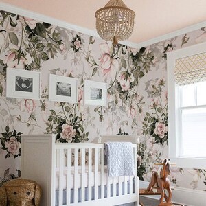 May include: A white crib with a floral wallpaper backdrop. The crib has a white mattress and a blue blanket. There is a wicker elephant toy basket next to the crib and a wooden rocking horse in the foreground. The text "Buy on kidsColoray Etsy Shop" is visible in the lower right corner of the image.