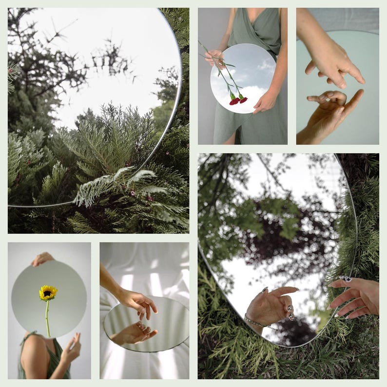 May include: A collection of round mirrors reflecting different scenes, including a sunflower, a hand, and a view of the sky through trees.