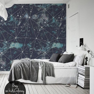 Può includere: Una camera da letto con un letto bianco e una carta da parati geometrica blu scuro con linee bianche e punti bianchi. La carta da parati ha un motivo simile a una galassia. Il letto ha una coperta grigia e cuscini neri. Il pavimento è in legno bianco.