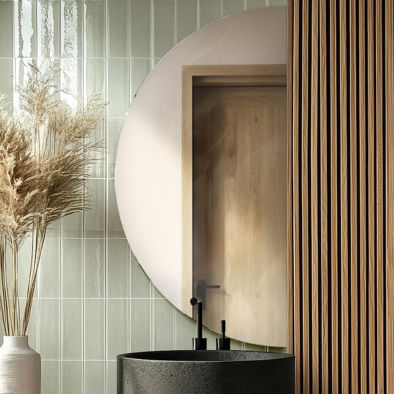 May include: A bathroom with green subway tiles, a round mirror, a black sink, and a wooden wall.
