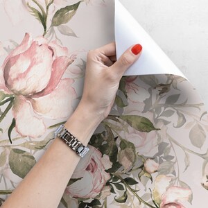 May include: A roll of pink and green floral wallpaper with a watercolor design. The wallpaper features a repeating pattern of pink roses and green leaves.