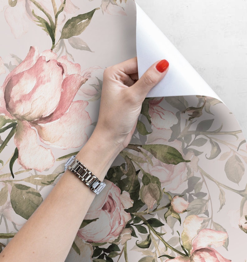May include: A roll of pink and green floral wallpaper with a watercolor design. The wallpaper features a repeating pattern of pink roses and green leaves.