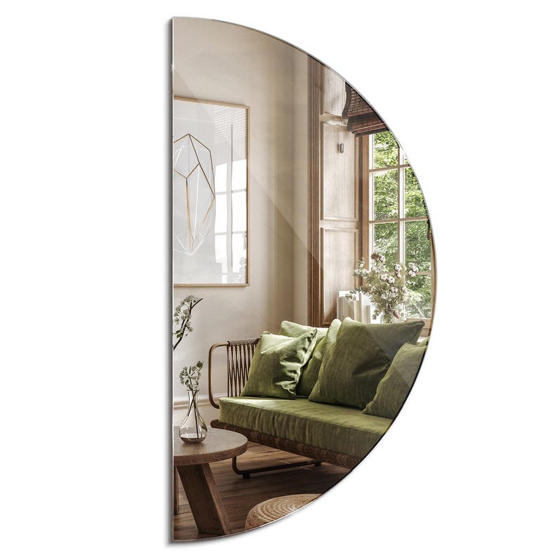 May include: A half-round mirror with a beveled edge reflects a living room with a green sofa, a wooden coffee table, and a framed print on the wall.