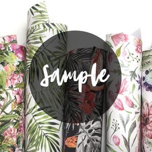 Puede incluir: Primer plano de cinco rollos de papel de regalo con diferentes patrones. Los rollos están dispuestos verticalmente y presentan varios diseños florales y tropicales. La palabra "Sample" está escrita en blanco sobre un círculo negro en el centro de la imagen.