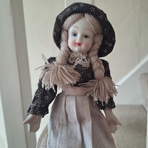 Bambola d&#39;epoca in bisquit con capelli in filato e viso dipinto a mano, personaggio da collezione.