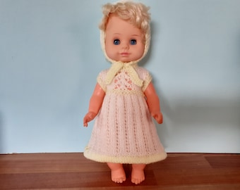 Jaren 70 vinylblonde pop met gele en blauwe slaapogen Verzamelaars speelgoed in handgebreide gele en crème jurk en muts.