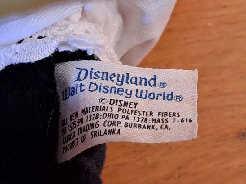 May include: White tag with blue text that reads "Disneyland Walt Disney World&reg;" and "&copy; DISNEY ALL NEW MATERIALS POLYESTER FIBERS 1525:PA 1378:OHIO PA 1378-MASS T-616 CANASA TRADING CORP. BURBANK, CA. PRODUCT OF SRILANKA".