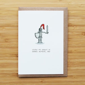 May include: Greeting card featuring a cartoon knight in silver armour, holding a sword and shield, and wearing a red helmet. The text reads, "You're my knight in shining armour, Dad."