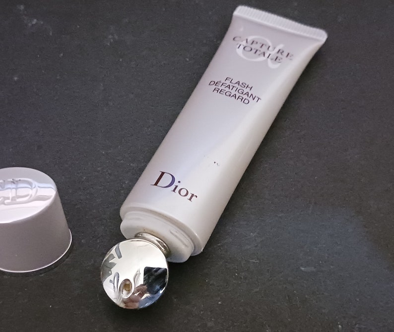 May include: A white tube of Dior Capture Totale Flash D&eacute;fatigant Regard eye cream with a silver rollerball applicator. The tube has the Dior logo and the product name printed on it.