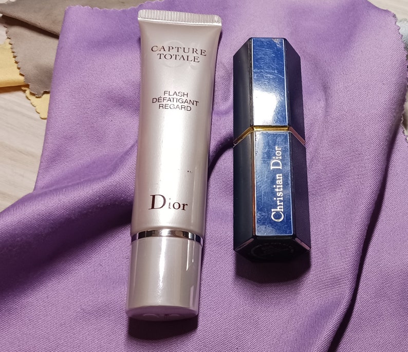 May include: Two Dior beauty products: a silver tube of Capture Totale Flash Defatiquant Regard and a blue and gold Christian Dior lipstick.