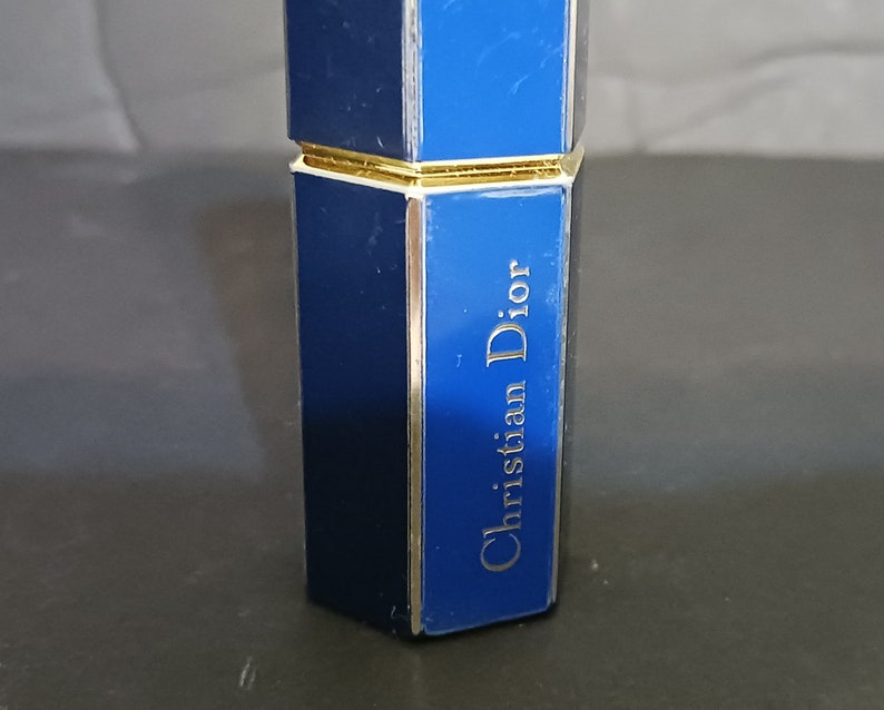 May include: A blue and gold perfume bottle with the text "Christian Dior" on the side.