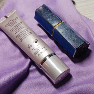 May include: A silver tube with a blue cap and a white label with black text. The text on the label reads "Flash Defatigant Regard Multi-Perfection Eye Treatment Anti-poches Multi-Perfection Instant Rescue Eye Treatment Anti-puffiness Anti-dark circles Multi Perfektion Soforteffekte Augenpflege Gegen Schwellungen und Augenschatten GM Made in France Parfums Christian Dior 75000 Paris 15 ml - 0.5 fl oz". A blue and gold lipstick tube is also in the image.