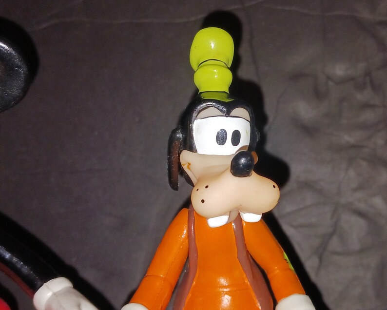 K&ouml;nnte beinhalten: Eine Comicfigur von Goofy, die einen gelben Hut und ein orangefarbenes Hemd tr&auml;gt. Er hat eine braune Nase und wei&szlig;e Augen.