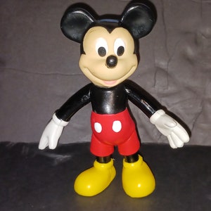 K&ouml;nnte beinhalten: Eine schwarze und rote Mickey Mouse Figur aus Plastik mit gelben Schuhen. Die Figur steht mit ausgestreckten Armen.