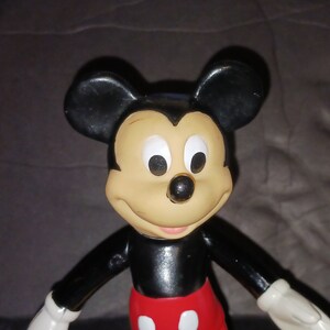 K&ouml;nnte beinhalten: Eine schwarze und rote Plastikfigur von Mickey Mouse mit gro&szlig;en Ohren und einem freundlichen L&auml;cheln.