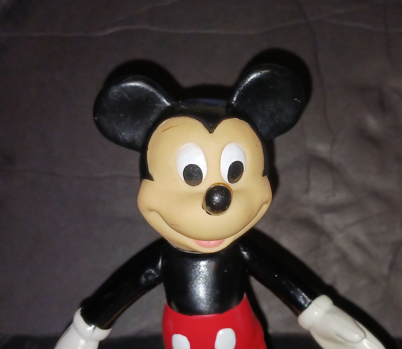 K&ouml;nnte beinhalten: Eine schwarze und rote Plastikfigur von Mickey Mouse mit gro&szlig;en Ohren und einem freundlichen L&auml;cheln.