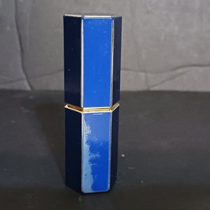 May include: A blue and gold octagonal lipstick tube with a gold band around the middle.