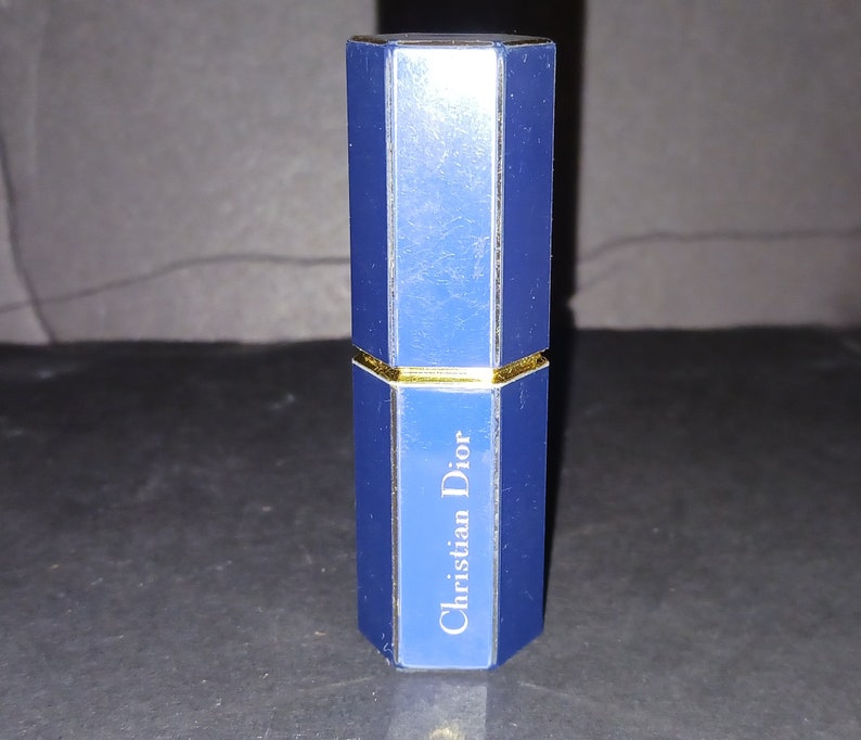 May include: A blue and gold octagonal shaped perfume bottle with the text "Christian Dior" on the front.