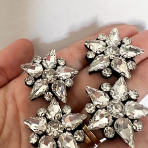 May include: Four silver star-shaped embellishments with clear rhinestones. Each star is approximately 2 inches in diameter.