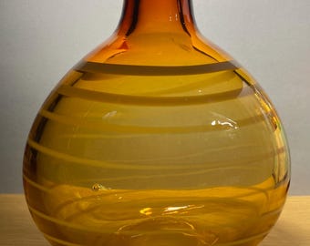 May include: A clear glass vase with a wide, round body and a narrow neck. The vase has a brown and yellow striped pattern.