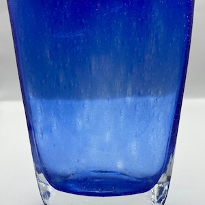 K&ouml;nnte beinhalten: Eine blaue Glasvase mit strukturierter Oberfl&auml;che. Die Vase hat einen klaren Glasboden.