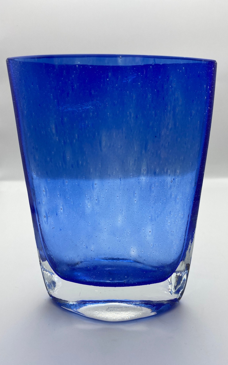 K&ouml;nnte beinhalten: Eine blaue Glasvase mit strukturierter Oberfl&auml;che. Die Vase hat einen klaren Glasboden.