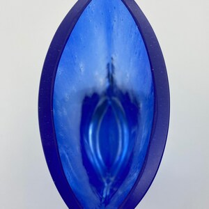 K&ouml;nnte beinhalten: Eine blaue Glasvase mit wei&szlig;em Innenraum und einer einzigartigen, organischen Form. Die Vase hat eine gl&auml;nzende Oberfl&auml;che und eine breite &Ouml;ffnung.
