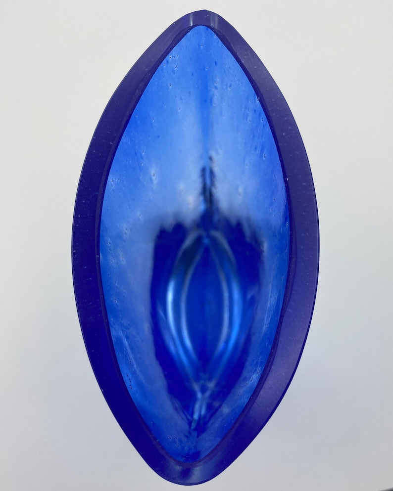 K&ouml;nnte beinhalten: Eine blaue Glasvase mit wei&szlig;em Innenraum und einer einzigartigen, organischen Form. Die Vase hat eine gl&auml;nzende Oberfl&auml;che und eine breite &Ouml;ffnung.