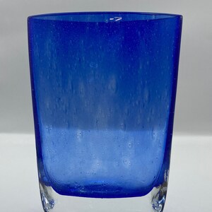 K&ouml;nnte beinhalten: Ein blauer Glasbecher mit strukturierter Oberfl&auml;che. Das Glas hat einen klaren Boden und eine blaue Oberseite.