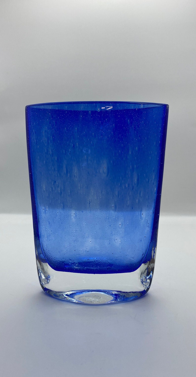 K&ouml;nnte beinhalten: Ein blauer Glasbecher mit strukturierter Oberfl&auml;che. Das Glas hat einen klaren Boden und eine blaue Oberseite.
