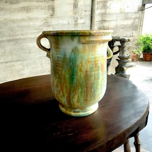 May include: A large, ceramic vase with two handles. The vase has a mottled glaze in shades of green, brown, and white.