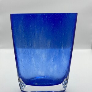 K&ouml;nnte beinhalten: Eine blaue Glasvase mit strukturierter Oberfl&auml;che. Die Vase hat einen klaren Boden und eine abgerundete rechteckige Form.