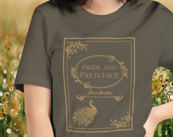 May include: Olive green t-shirt featuring a gold-colored design of a book cover with the words "Pride and Prejudice" and "Jane Austen." The design includes floral accents and a peacock illustration.