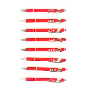 May include: A collection of eight red pens with silver accents and the Greek letters ΔΣΘ printed on the barrel. Each pen has a stylus tip. The pens are arranged on a white background.