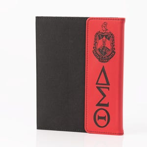 May include: A black and red wallet with a Greek letter design. The wallet has a black fabric body and a red leather flap with a black emblem and Greek letters. The wallet is closed and upright.