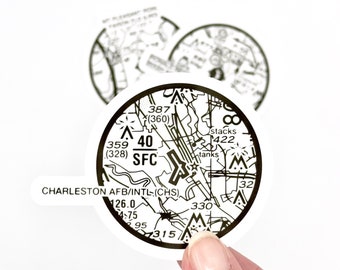 Pode incluir: Um adesivo circular preto e branco com um mapa detalhado do aeroporto Charleston AFB/INTL. O adesivo inclui o identificador do aeroporto (CHS), a altitude (40 SFC) e outras informações de navegação.