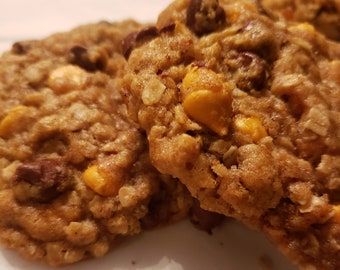 May include: Close-up of three oatmeal cookies with chocolate chips and butterscotch chips. The cookies are golden brown and have a slightly crispy texture.