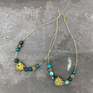 May include: A pair of owl charm earrings with blue and green agate beads. The earrings are made with gold-toned wire and feature a small owl charm on each earring.