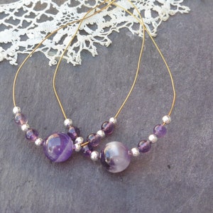 May include: Two gold hoop earrings with purple amethyst beads and silver spacer beads.